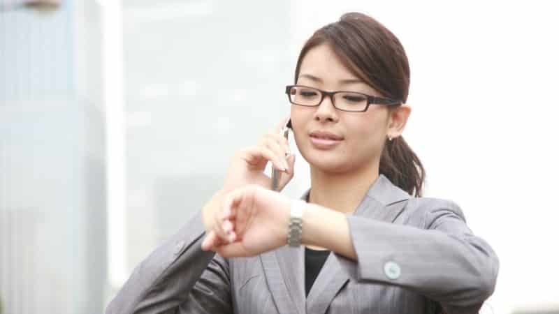 Woman in gray striped suit on cellphone looking at watch