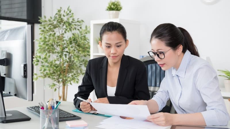 Two women in business attire review a document