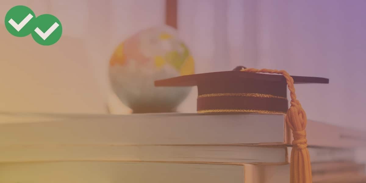 Graduation cap on stack of books symbolizing grad school - image by Magoosh
