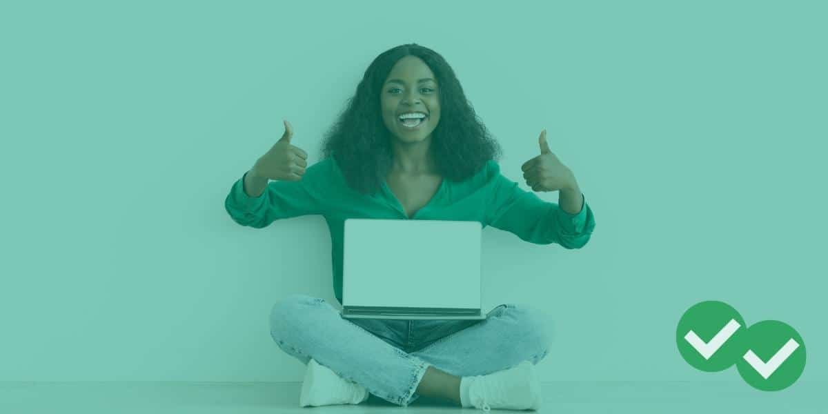 A student with a laptop giving a double thumbs up