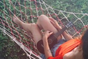 girl on hammock with a ukulele outside with her face out of the frame -image by tyson4ik