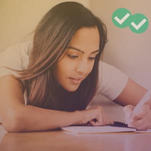 Student writing in notebook to show best IELTS writing resources