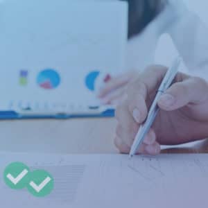 Person holding paper with multiple IELTS graphics while another person marks a separate sheet of graphs - image by Magoosh