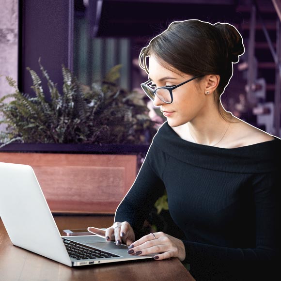 woman with dark hair in bun and glasses working at laptop