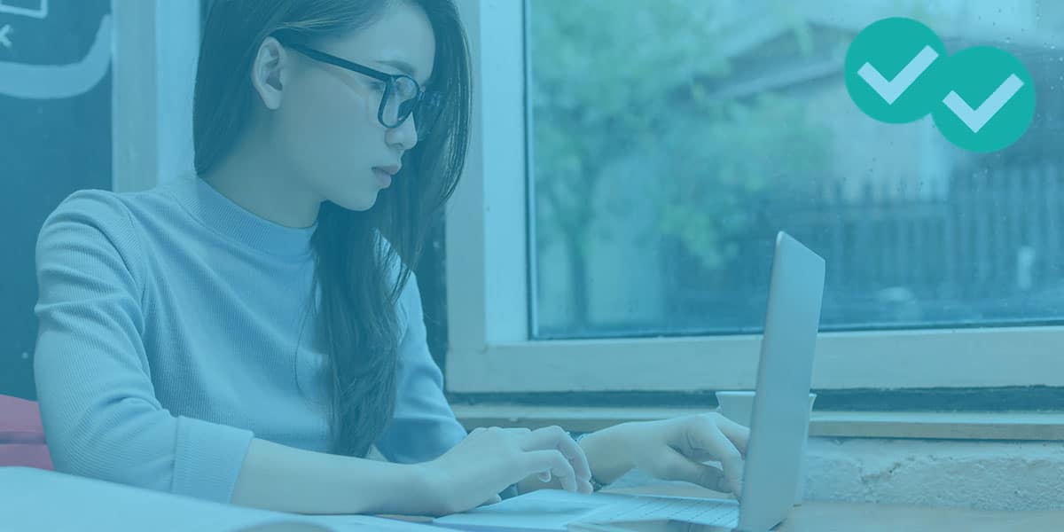 a young woman with glasses working on a laptop to represent psat practice - image by Magoosh