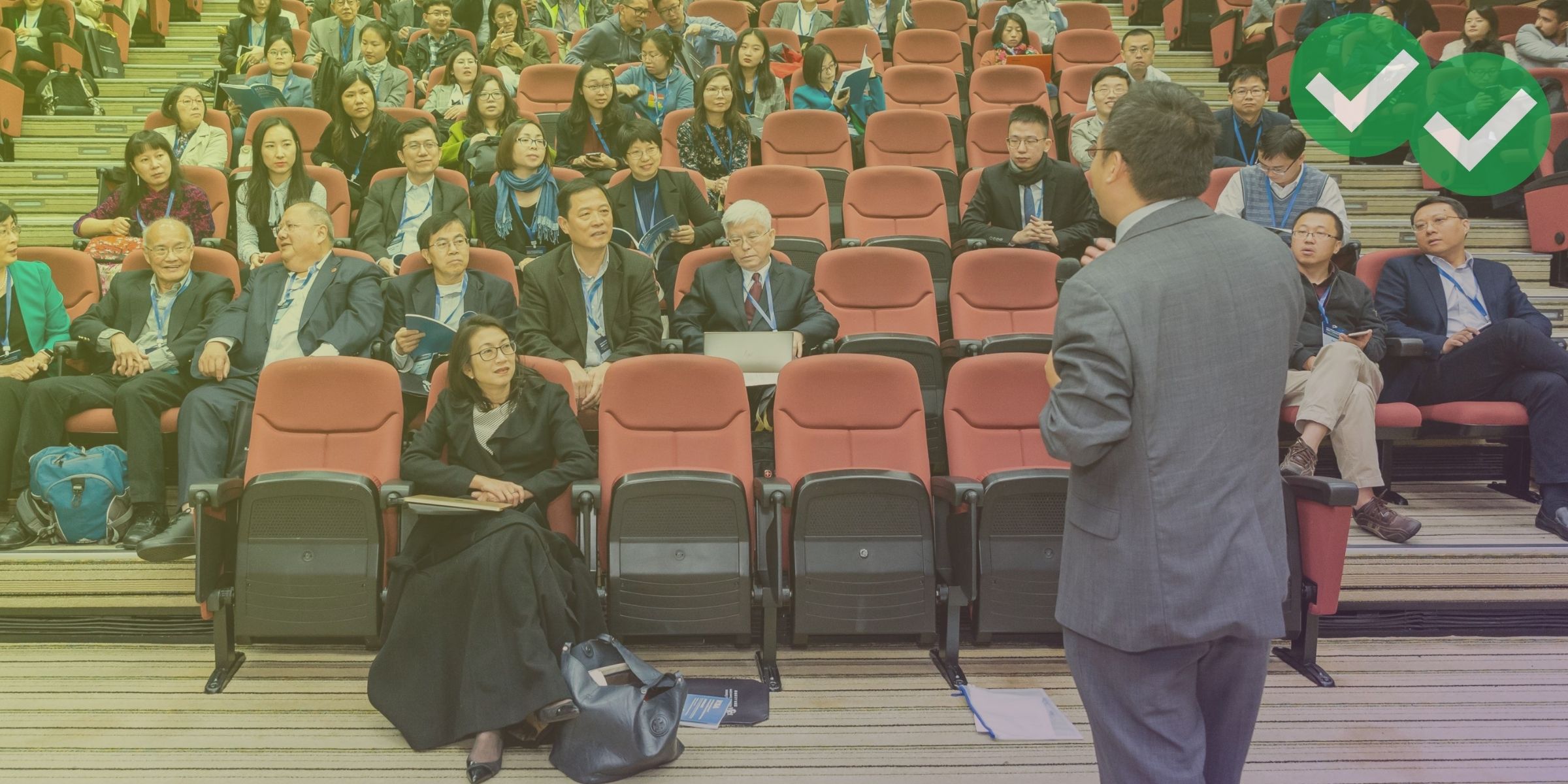 Speaker faces an auditorium of adult students representing the TOEFL speaking template - image by Magoosh