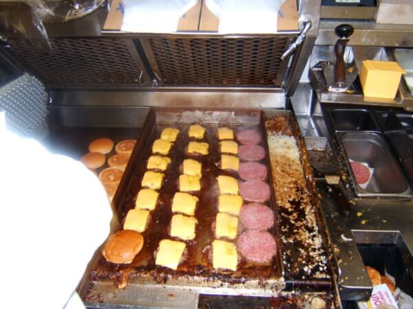 Cheeseburgers frying on a grill